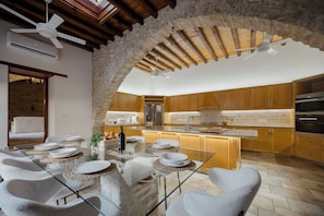 A modern kitchen with an island, stone archway, and wooden cabinets. - The Bakery - A Luxury Village Stone House with Pool. Pet Friendly! (Kalavasos)