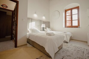 Une chambre d’hôtel avec deux lits, une porte en bois, une bibliothèque et une fenêtre donnant sur un paysage agréable.