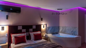 A modern bedroom with a large bed, a built-in bathtub, and a wall-mounted air conditioning unit. - Portovo Private Jacuzzi & AC Suite (Gdańsk)