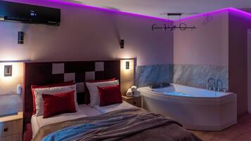 A modern bedroom with a large bed, a built-in bathtub, and a wall-mounted air conditioning unit.