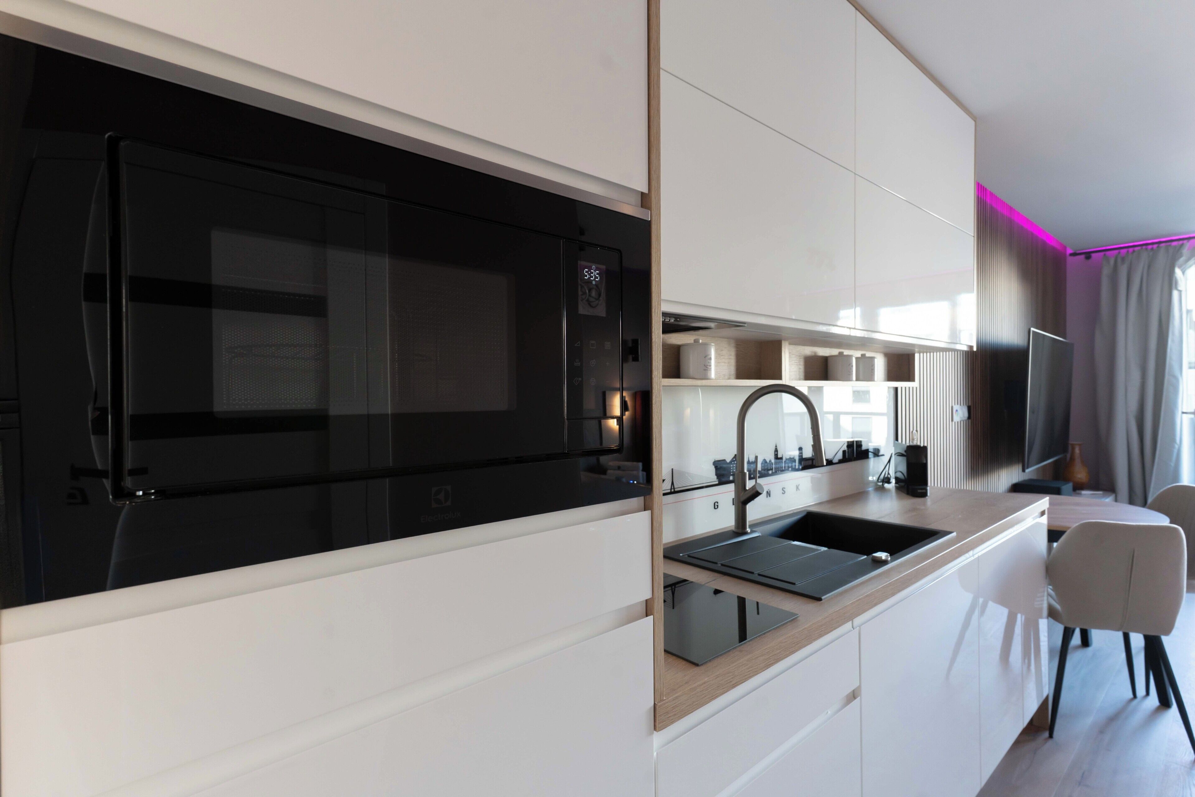 A modern kitchen with a black stove, white cabinets, and a built-in sink.