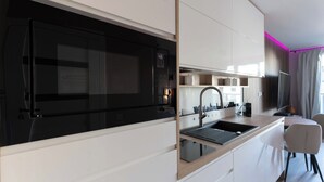 A modern kitchen with a black stove, white cabinets, and a built-in sink. - Portovo Private Jacuzzi & AC Suite (Gdańsk)