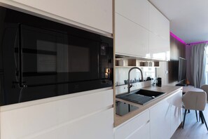 A modern kitchen with a black stove, white cabinets, and a built-in sink. - Portovo Private Jacuzzi & AC Suite (Gdańsk)