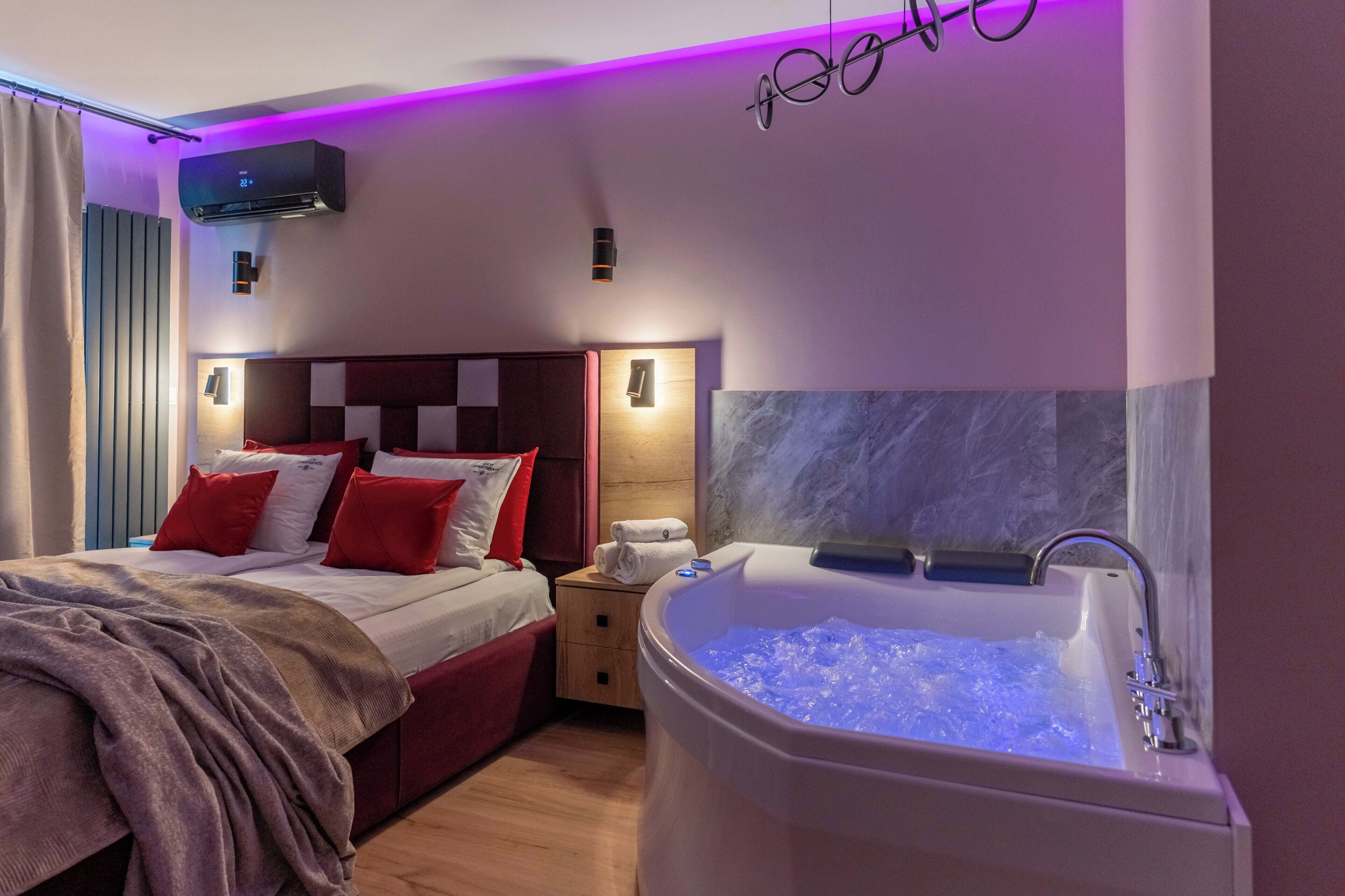 Habitación de hotel con cama, mesita de noche, baño con bañera y aire acondicionado instalado en la pared.