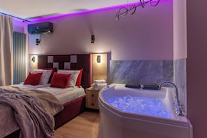 Habitació d'hotel amb un llit, una taula de nit, un bany amb banyera i un aire condicionat fixat a la paret.