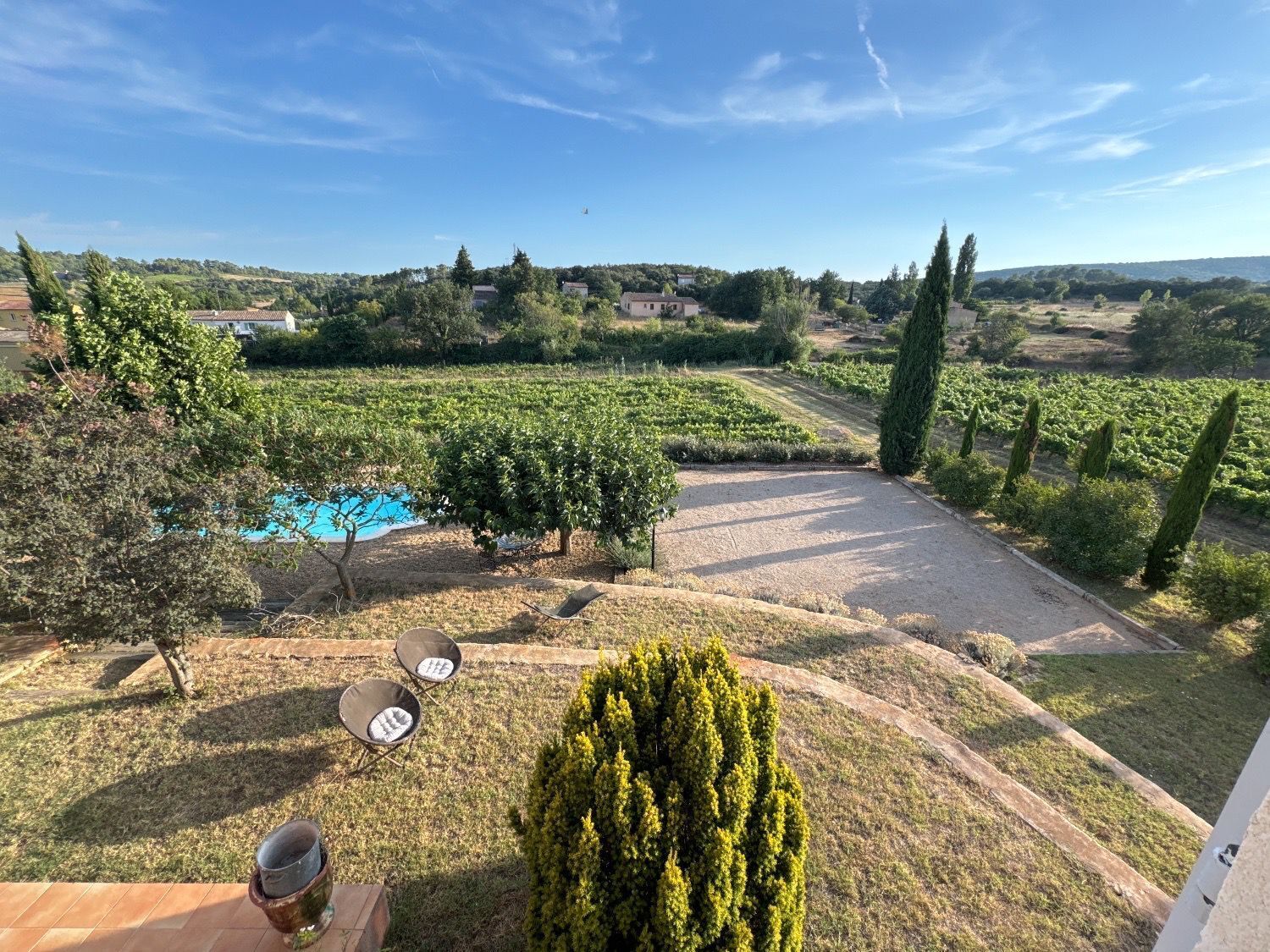 A vineyard with a swimming pool, outdoor seating, and a view of the surrounding landscape.