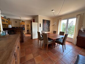 A spacious kitchen with a dining area, a large window, and a painting on the wall. - Maison chaleureuse de 5 chambres située en Provence idéale pour les familles (Brue-Auriac)