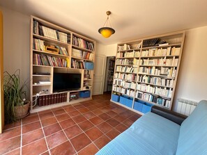 A living room with a television, bookshelves, a sofa, and a potted plant. - Maison chaleureuse de 5 chambres située en Provence idéale pour les familles (Brue-Auriac)