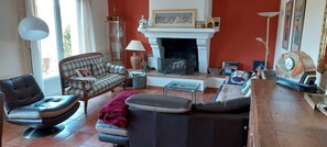 A living room with a fireplace, a sofa, a chair, and a coffee table. - Maison chaleureuse de 5 chambres située en Provence idéale pour les familles (Brue-Auriac)