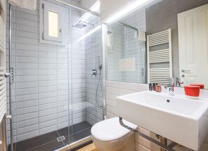 Ein modernes Badezimmer mit Duschkabine aus Glas, Waschbecken in Weiß und Toilette.