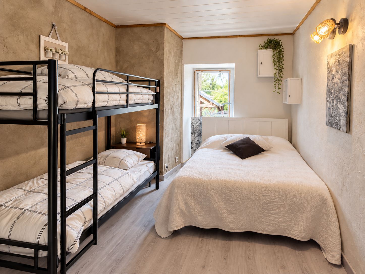 Quarto com beliche, uma mesa de cabeceira com luminária, janela com vista para vegetação e armário fixado na parede.