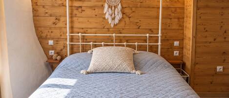 A bed with a white metal frame, a blue quilted bedspread, and a white canopy.