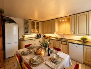 Eine Küche mit Esstisch, gedecktem Tisch für eine Mahlzeit, Kühlschrank, Schränken und einem Geschirrspüler.