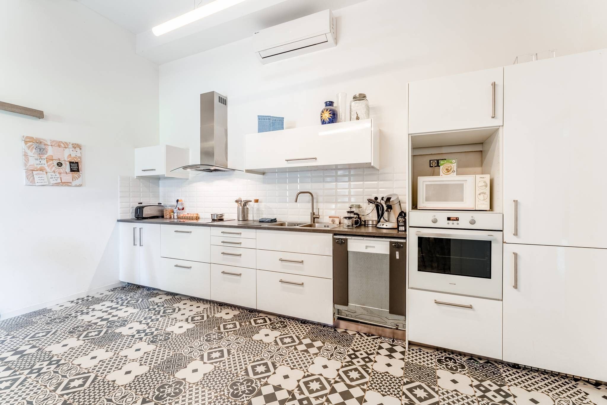 A modern kitchen with white cabinets, a patterned floor, and a built-in microwave.