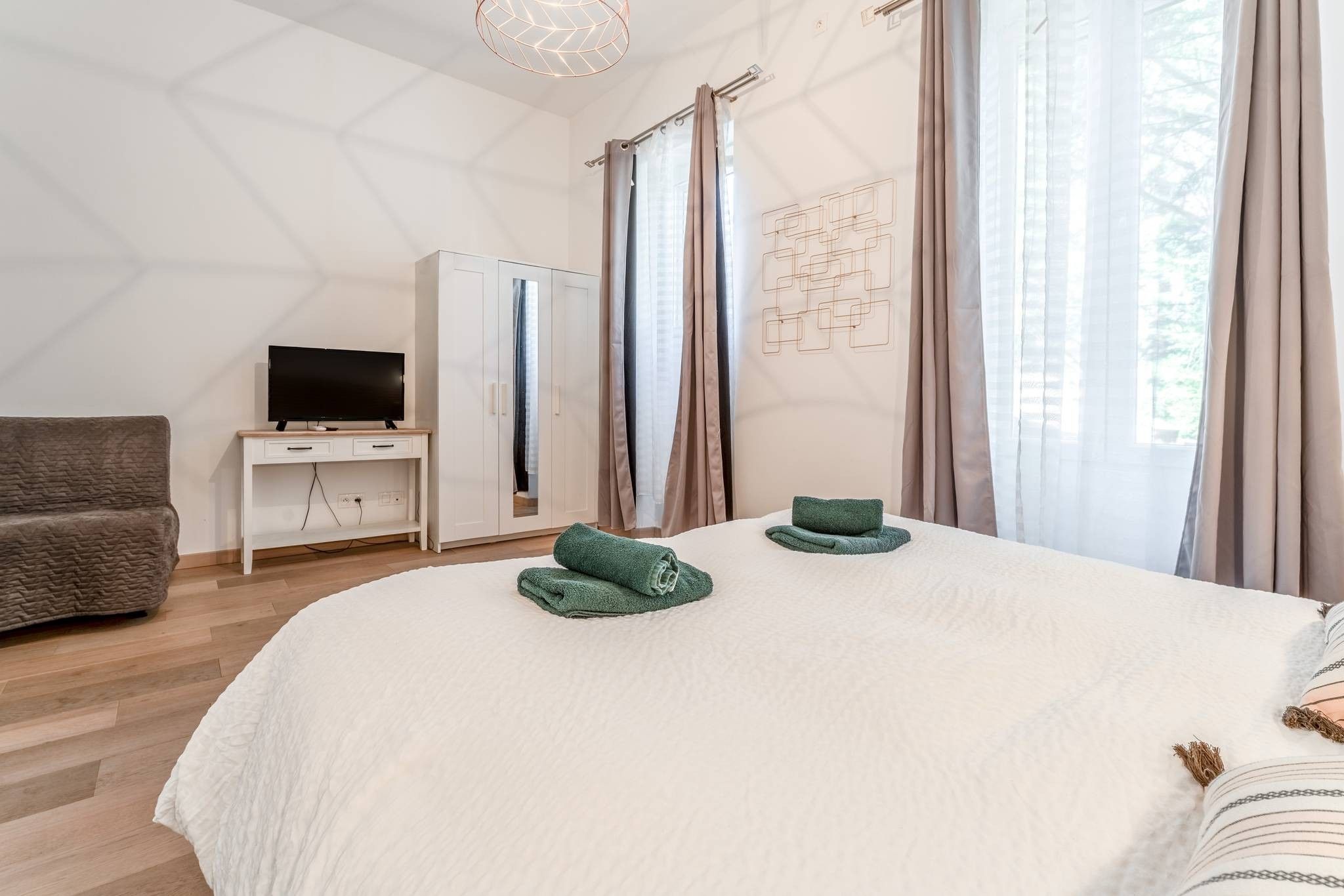 Un dormitorio con una cama, un televisor sobre un mueble bajo, un armario y un sofá.