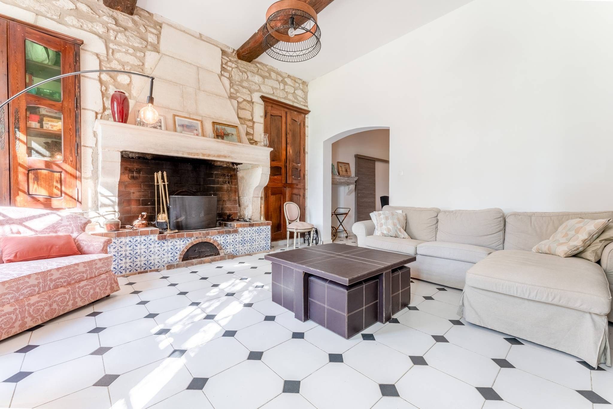 Un salón con chimenea de piedra, un sofá, una mesa de centro y un suelo estampado.