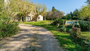 A gravel path leading to a building with a pool, surrounded by lush greenery and trees. - Holiday Home 'Le Mas De KItty' with Private Pool, Wi-Fi and Air Conditioning (Saint-Rémy-de-Provence)