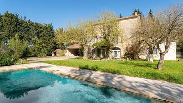 Une piscine à l’eau d’un bleu cristallin, entourée d’une pelouse bien entretenue et d’arbres.