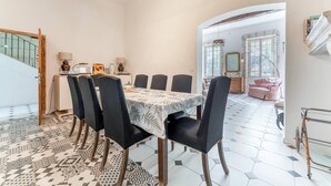 A dining area with a table set for six, surrounded by chairs, in a room with a staircase and a view of the outside. - Holiday Home 'Le Mas De KItty' with Private Pool, Wi-Fi and Air Conditioning (Saint-Rémy-de-Provence)