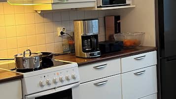 Cozinha com armários brancos, micro-ondas, cafeteira e geladeira.