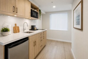 Een moderne keuken met houten kastjes, een RVS vaatwasser, een magnetron en een spoelbak.