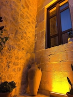Un muro de piedra con un jarrón grande y plantas en macetas.
