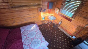 Una habitación con cama, una mesita con sillas, un mapa mundial en la pared y una ventana con persianas.