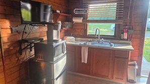 Cocina compacta con microondas integrado, cafetera y lavamanos.