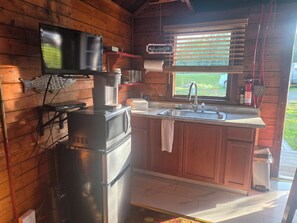 A compact kitchen with a built-in microwave, a coffee maker, and a sink.