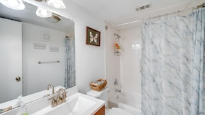 Un bagno con lavandino bianco, uno specchio, un WC e una zona doccia.