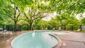 Una piscina a bordo curvo, circondata da una recinzione in metallo nero e alberi.