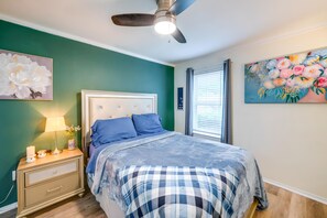 Quarto com cama, mesa de cabeceira e ventoinha no teto.