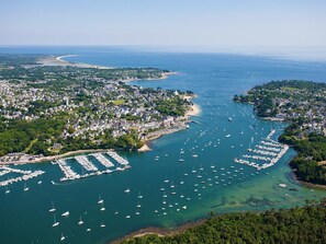 An aerial view of a coastal town with a marina filled with boats, surrounded by residential areas and a beach. - House on a quiet street near the beaches (Bénodet)