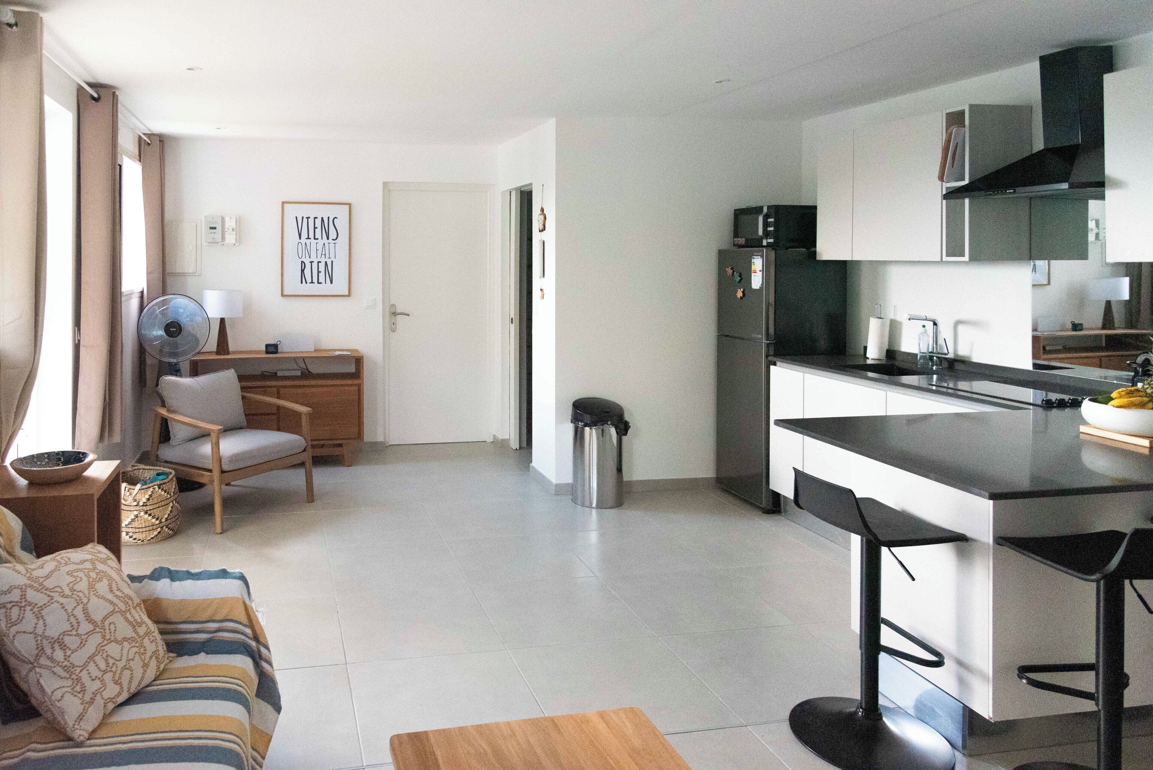 Een moderne keuken met een koelkast, magnetron en barstoelen.