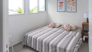 Una camera da letto con un letto, due cuscini, un comodino, una lampada e due quadri appesi al muro.