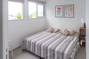 Ein Schlafzimmer mit einem Bett, zwei Kissen, einem Nachttisch, einer Lampe und zwei gerahmten Bildern an der Wand.