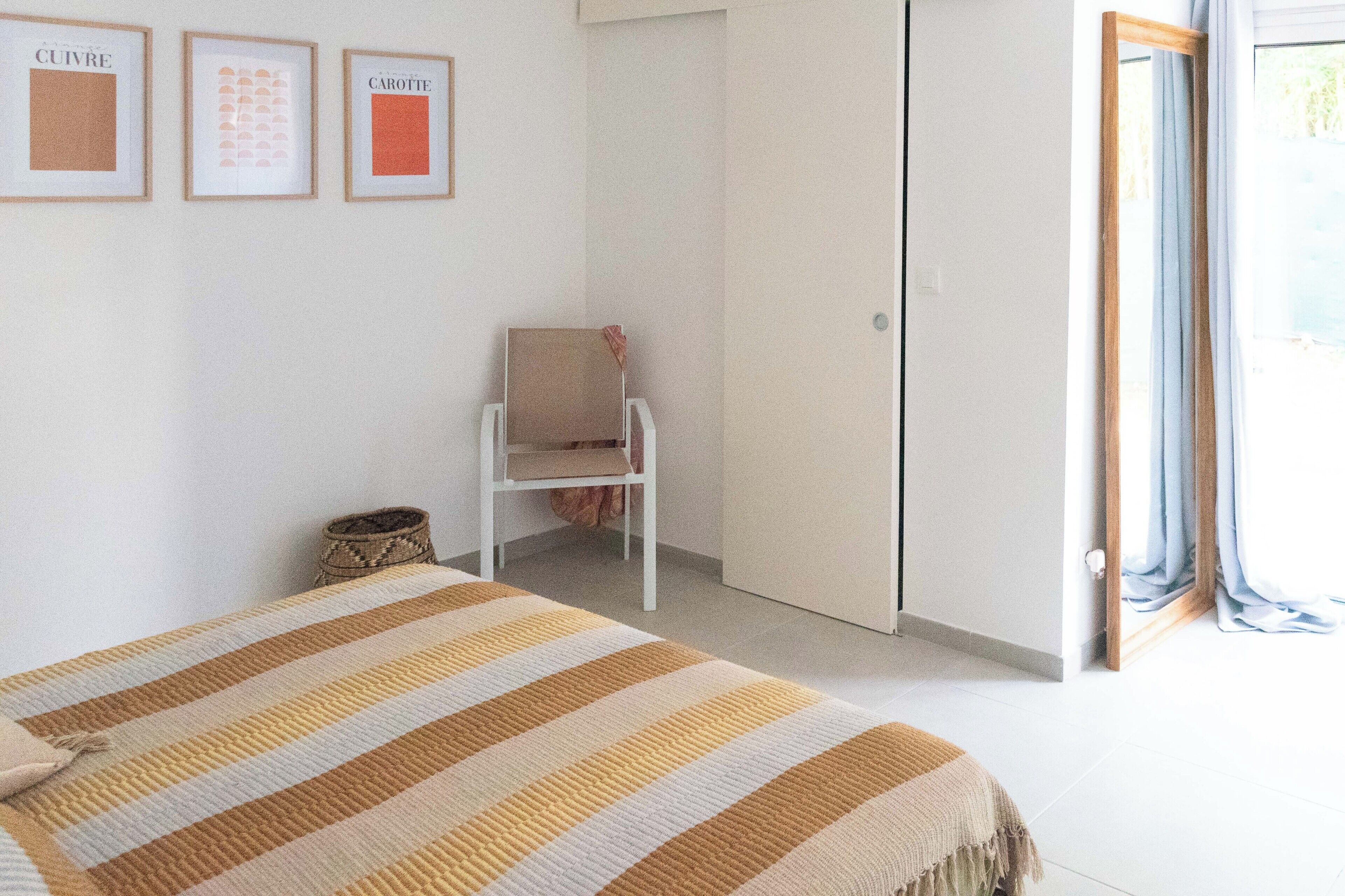A bedroom with a bed, a chair, and a wardrobe.