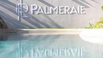 Ein klares Schwimmbecken, in dessen Spiegelung der Schriftzug 'PALMERAEI' an der Wand zu sehen ist.