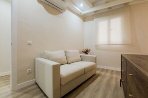 Ein sofas in neutralen Farben in einem Zimmer mit einem Holzkabinett und einer Wand-Klimaanlage.