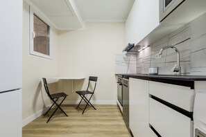 A compact kitchen with a built-in oven, a microwave, and a sink. There are two foldable chairs and a window above the sink. - Two-bedroom apartment in downtown Barcelona 2-2 (Barcelona)