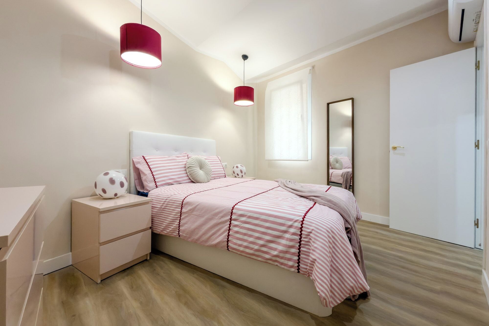 A bedroom with a bed, bedside tables, a mirror, and a wardrobe.