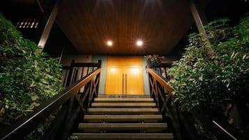 Una escalera conduce a una puerta de madera, con barandales metálicos a ambos lados.