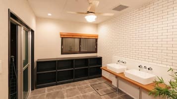 Un baño con dos lavamanos, un ventilador de techo y una ventana.