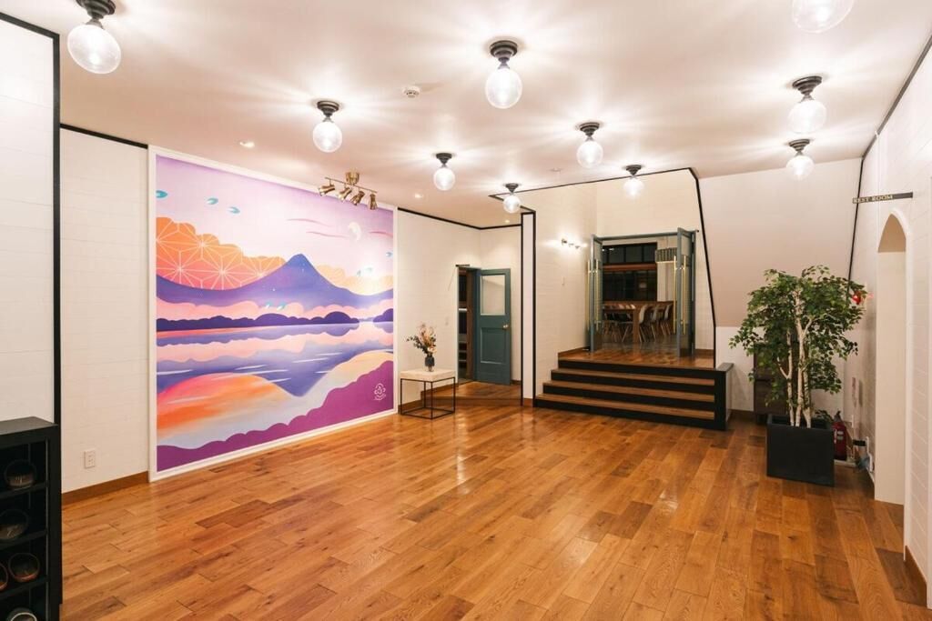 A spacious room with a wooden floor, a staircase, and a colorful mural on the wall.