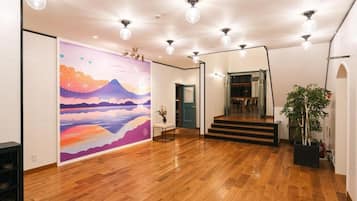 A spacious room with a wooden floor, a staircase, and a colorful mural on the wall.