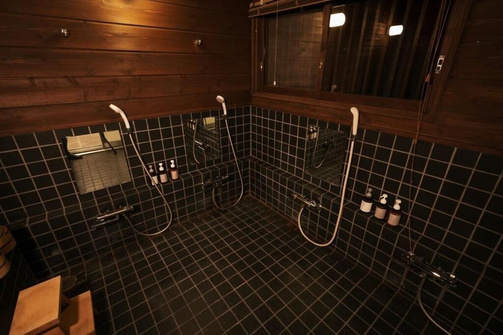 Un baño con pared de madera, suelo de baldosas negras y una ventana.