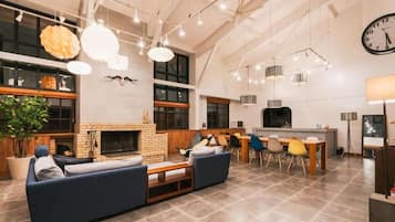 A spacious living area with a fireplace, a dining table with chairs, and a kitchen area.