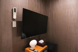 A room with a mounted flat-screen TV, a remote control, a tissue box, and a wall-mounted thermostat. - Fujisan Lodge En (Minamitsuru-gun, Fujikawaguchiko machi,)