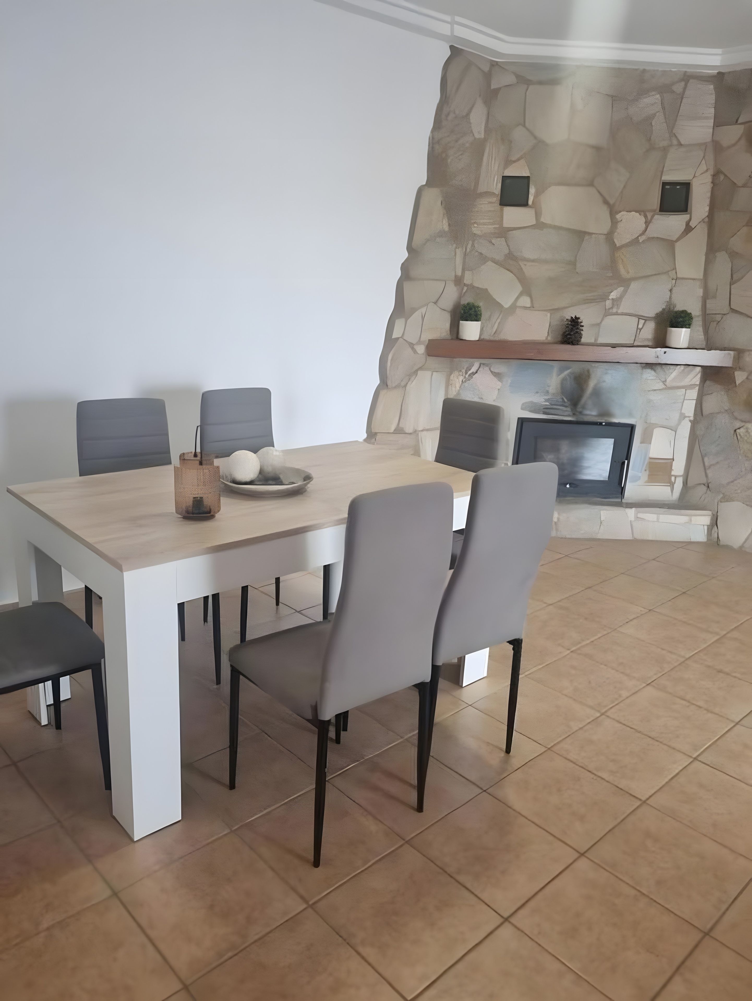 Zona pranzo con parete in pietra, camino e tavolo moderno con sedie.