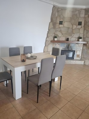 Zona pranzo con parete in pietra, camino e tavolo moderno con sedie.